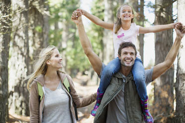 Father carrying daughter on shoulders in woods - CAIF28555