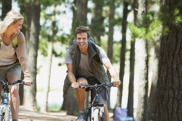 Lächelndes Paar beim Mountainbiking im Wald - CAIF28557