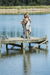 Smiling couple hugging on dock over lake - CAIF28563