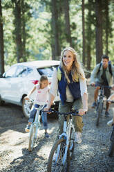 Lächelnde Familie beim Radfahren im Wald - CAIF28564