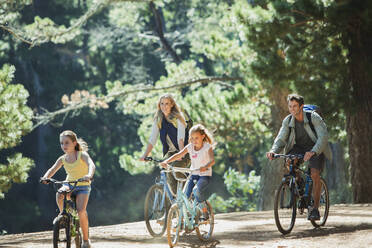 Lächelnde Familie beim Radfahren im Wald - CAIF28565