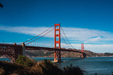 Amazing red bridge above river near rock hills and wonderful blue sky - ADSF06193