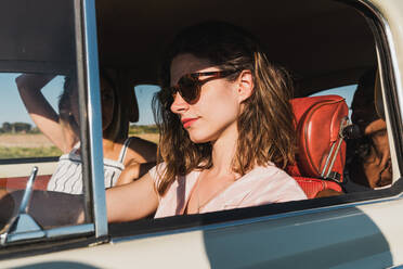 Gruppe glücklicher multiethnischer Frauen im Auto, die im hellen Sonnenlicht zusammen fahren und lachen - ADSF06201