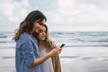 Zwei lächelnde Freunde machen ein Selfie am Meeresufer - ADSF06261