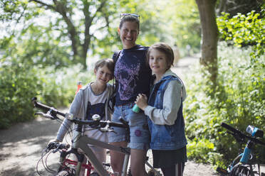 Porträt glückliche Mutter und Söhne genießen Fahrradtour in sonnigen Park - CAIF28576