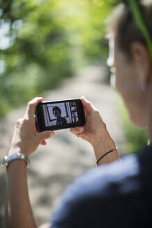 Frau im Videochat mit Freunden auf dem Bildschirm eines Smartphones - CAIF28579