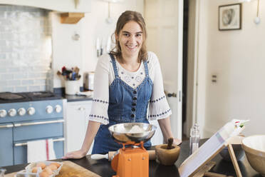 Porträt selbstbewusstes Teenager-Mädchen beim Backen in der Küche - CAIF28620