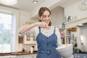 Happy teenage girl baking in kitchen - CAIF28635