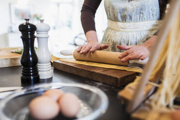 Woman rolling dough with rolling pin in kitchen - CAIF28647