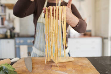 Close up woman making fresh homemade pasta in kitchen - CAIF28655