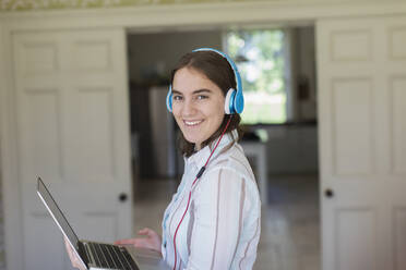 Porträt selbstbewusstes Teenager-Mädchen mit Kopfhörern und Laptop - CAIF28679
