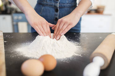 Close up teenage girl making flour nest on kitchen counter - CAIF28686