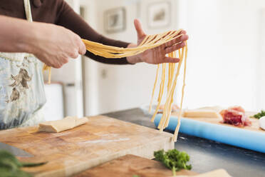 Close up woman making fresh homemade pasta in kitchen - CAIF28693