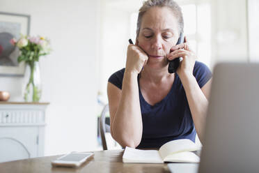 Woman working from home talking on telephone - CAIF28694