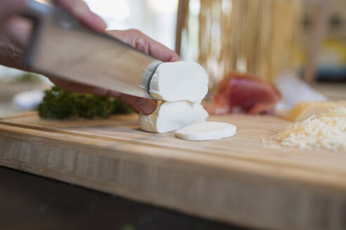 Close up knife cutting into fresh mozzarella cheese - CAIF28707