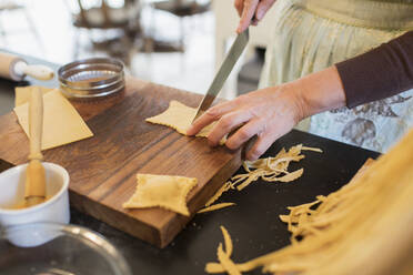 Close up woman cutting fresh homemade pasta - CAIF28714