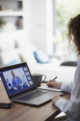 Woman video conferencing with doctor on laptop screen - CAIF28757