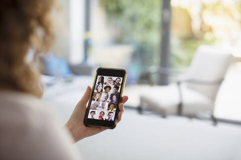 Frau im Videochat mit Freunden auf dem Bildschirm eines Smartphones, lizenzfreies Stockfoto