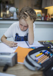 Focused boy home schooling at table - CAIF28779