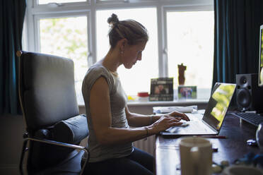 Frau arbeitet von zu Hause aus am Laptop im Home Office - CAIF28786