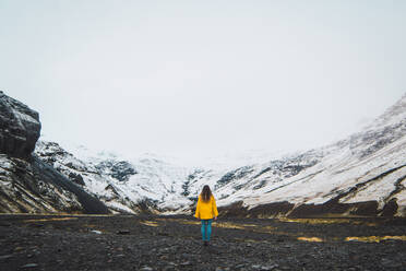 Frau steht in der Nähe von verschneiten Bergen - ADSF06355