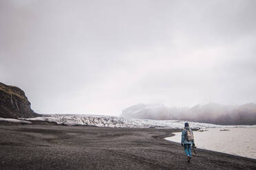Frau steht und genießt die Aussicht auf verschneite Berge - ADSF06367