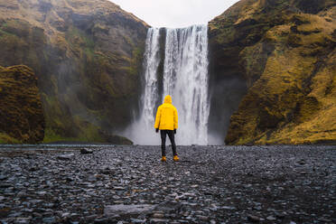 Mann steht in der Nähe eines Wasserfalls - ADSF06386