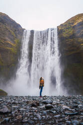 Frau steht in der Nähe eines Wasserfalls - ADSF06389