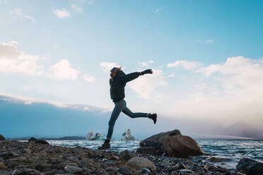 Happy girl balancing on rock in sea - ADSF06411