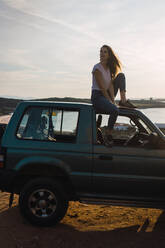 Woman sitting on car roof - ADSF06507