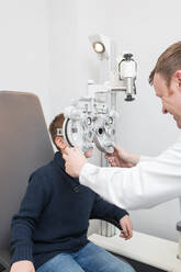 Optikerin testet die Augen eines Jungen mit optometrischen Geräten - ADSF06531