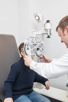Optician testing a boy's eyes with optometry devices - ADSF06531