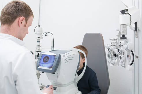 Optikerin testet die Augen eines Jungen mit optometrischen Geräten - ADSF06532