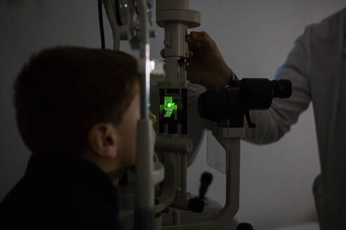 Optikerin testet die Augen eines Jungen mit optometrischen Geräten - ADSF06534