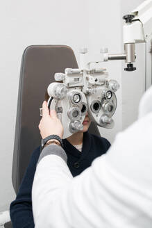 Optician testing a boy's eyes with optometry devices - ADSF06535