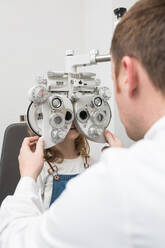 Optikerin testet die Augen eines Mädchens mit optometrischen Geräten - ADSF06536