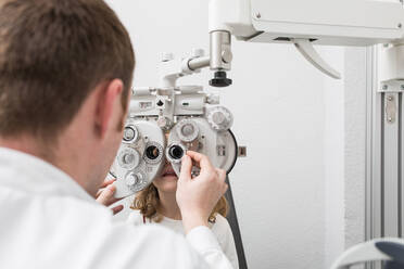 Optician testing a girl's eyes with optometry devices - ADSF06537