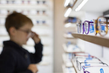 Cute young boy trying on glasses in an eyewear store - ADSF06540