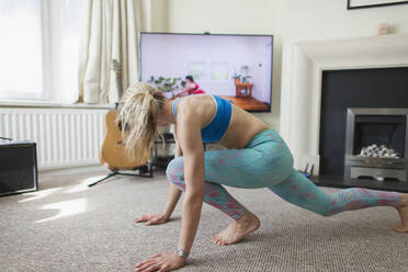 Frau praktiziert Online-Yoga im Wohnzimmer - CAIF28813
