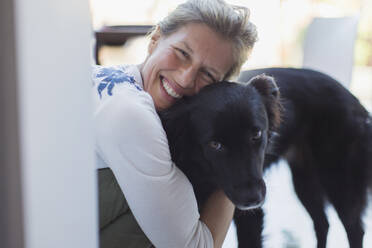 Porträt glückliche Frau umarmt Hund - CAIF28829