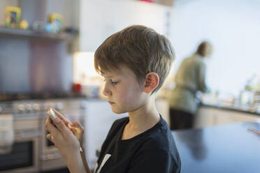 Junge benutzt Smartphone in der Küche - CAIF28845