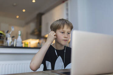 Boy with headphones homeschooling at laptop - CAIF28851