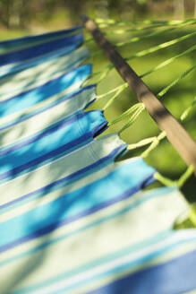 Close up sunshine over blue striped hammock - CAIF28925