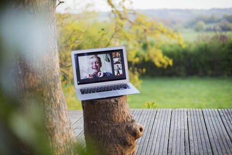 Friends video chatting on laptop screen on idyllic balcony stock photo