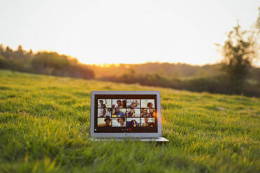 Freunde beim Videochat auf dem Laptop-Bildschirm im sonnigen Gras - CAIF28945