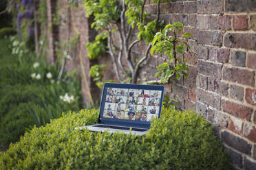 Freunde beim Videochat auf dem Laptop-Bildschirm im Garten - CAIF28957