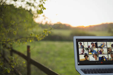 Freunde beim Videochat auf dem Laptop-Bildschirm am ländlichen Zaun - CAIF28964
