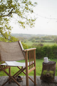 Book and chair on balcony overlooking rural field - CAIF28972