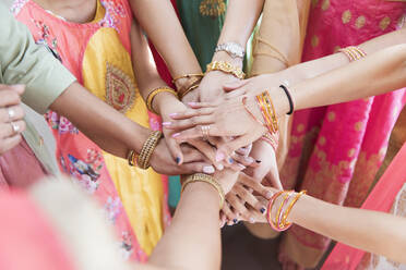 Indian women in bracelets joining hands in huddle - CAIF28986