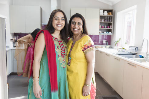 Portrait happy Indian sisters in traditional saris in kitchen - CAIF28998